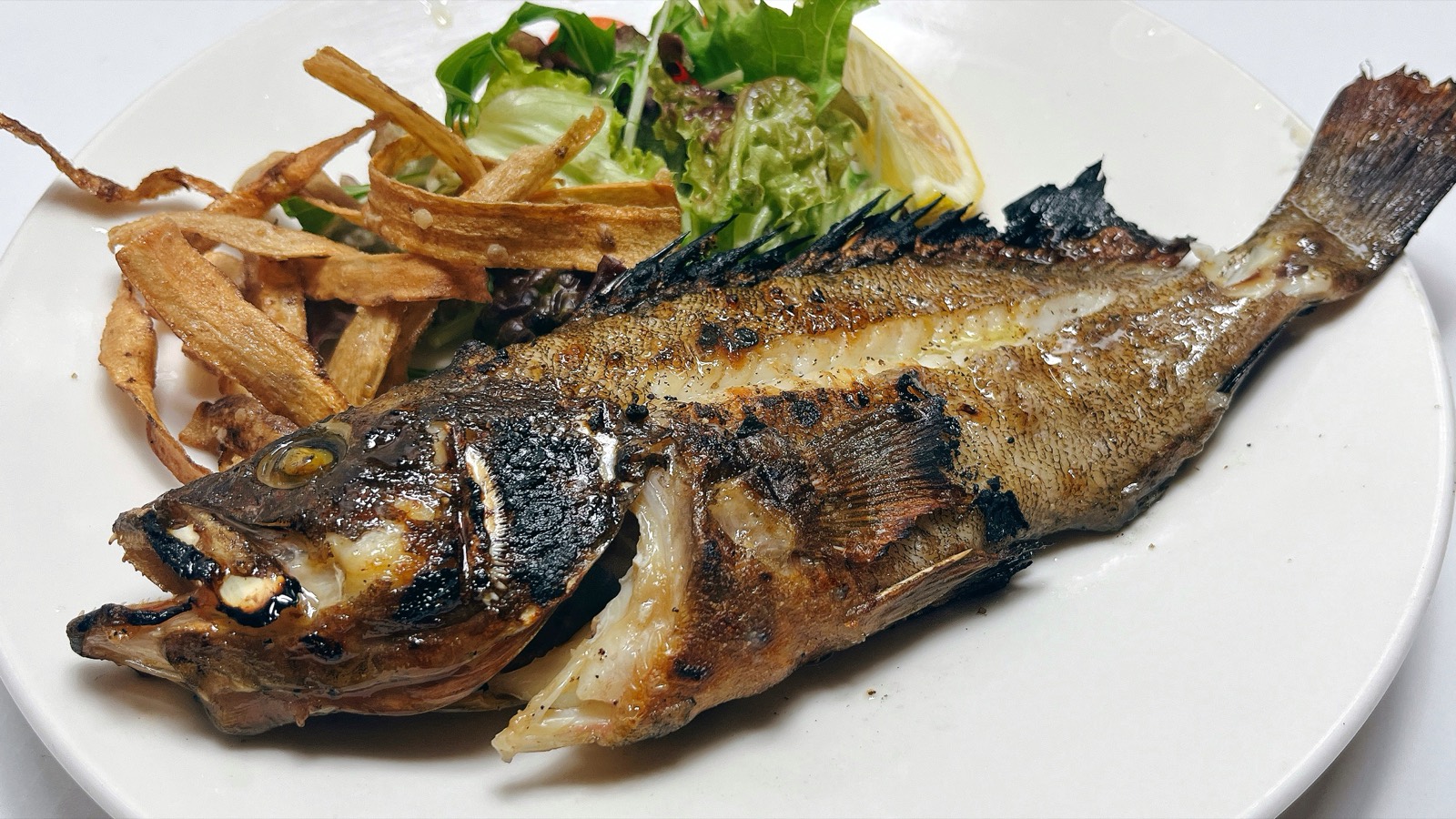 白い皿に盛りつけた魚の姿焼きと、素揚げにした野菜