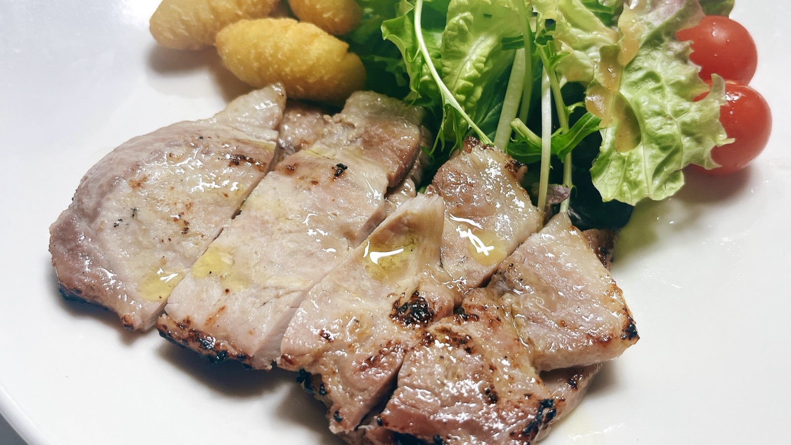 焼き上げた豚肉のスライスとサラダを盛りつけた皿