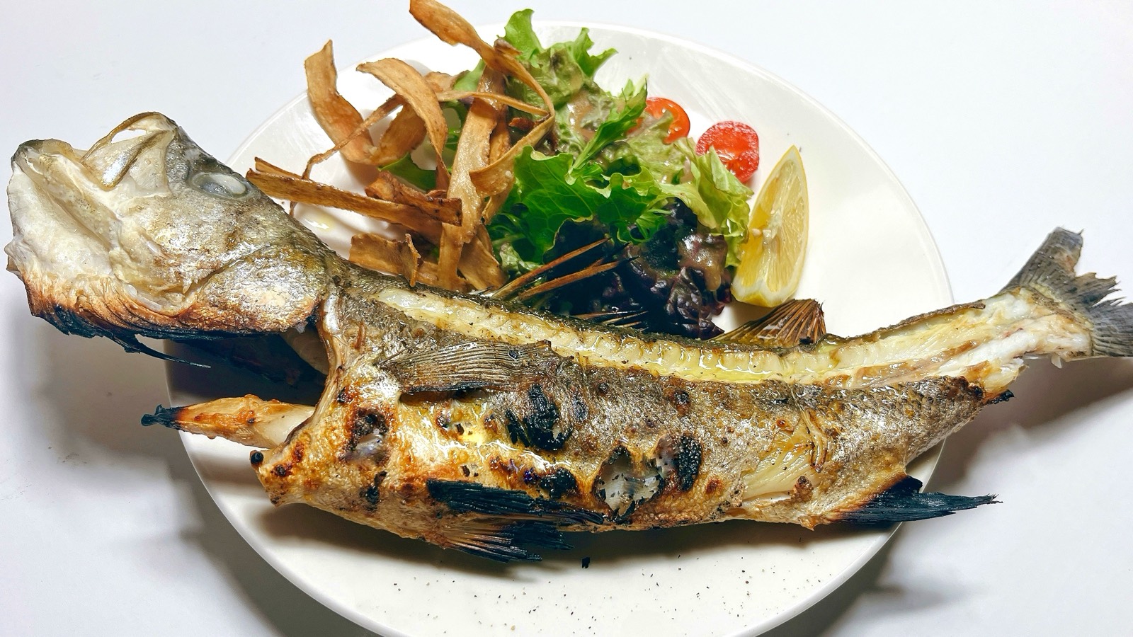 姿のまま焼いた魚に、揚げた野菜とレモンを添えた一皿