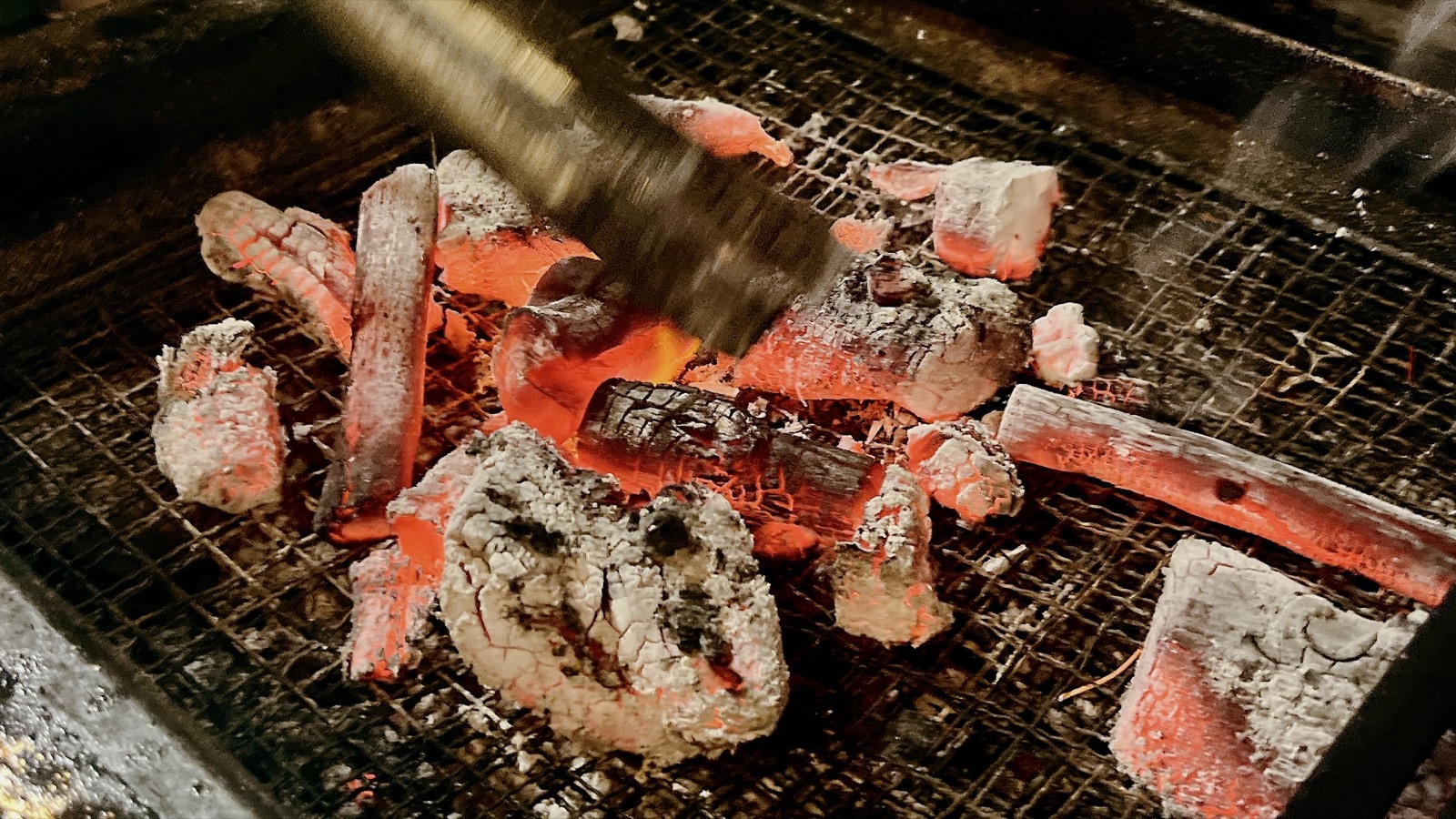 赤く熾った炭火の上の網で食材を焼いているところ